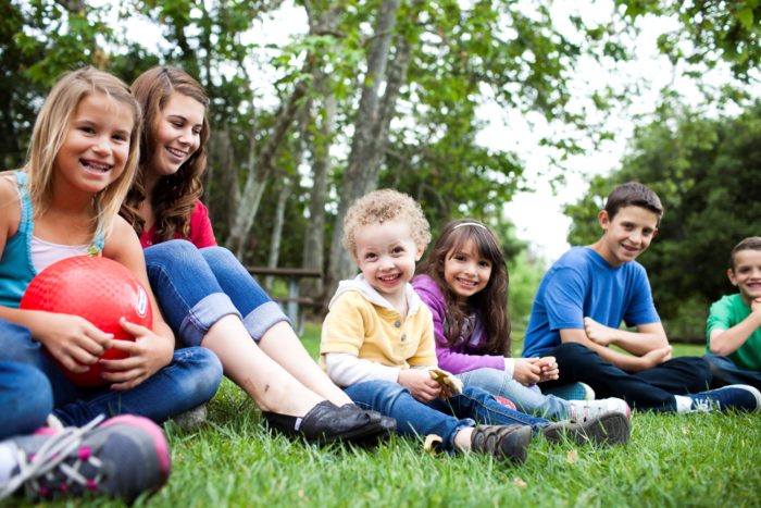 group of children sitting in grass in the park